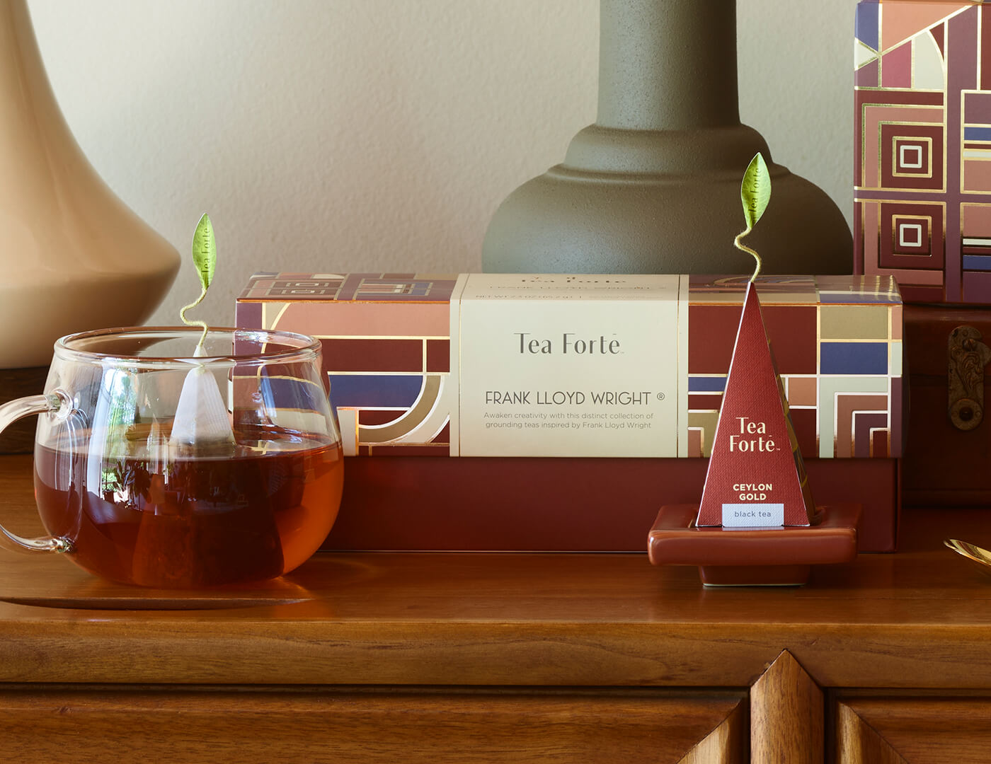 Frank Lloyd Wright Presentation Box, closed o a modern wooden table with glass teacup and tea infuser